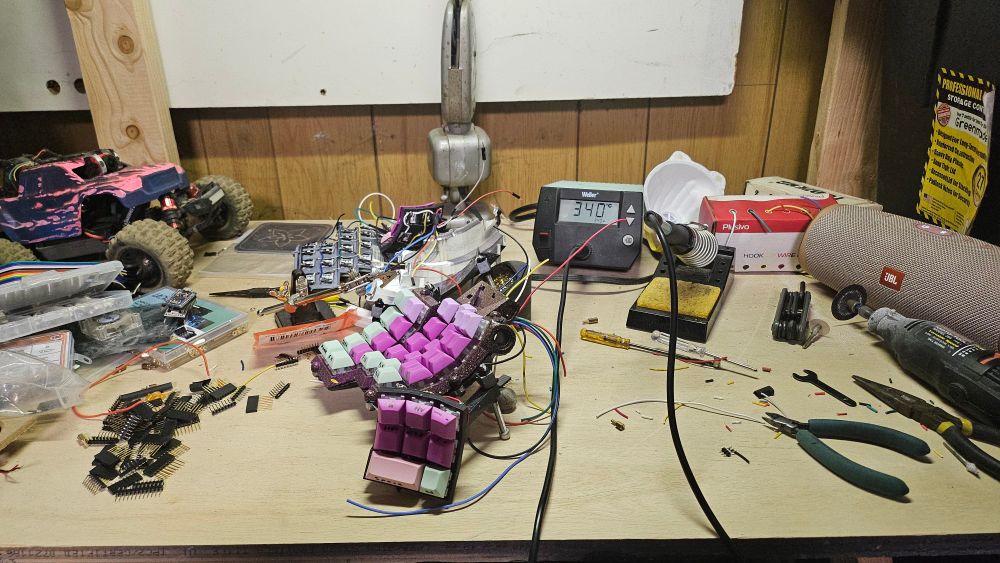 A mess of wires and buttons on a work bench along with a soldering iron