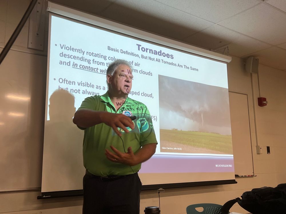 A man standing in front of a projected slide that says, “Tornadoes: Basic Definition”