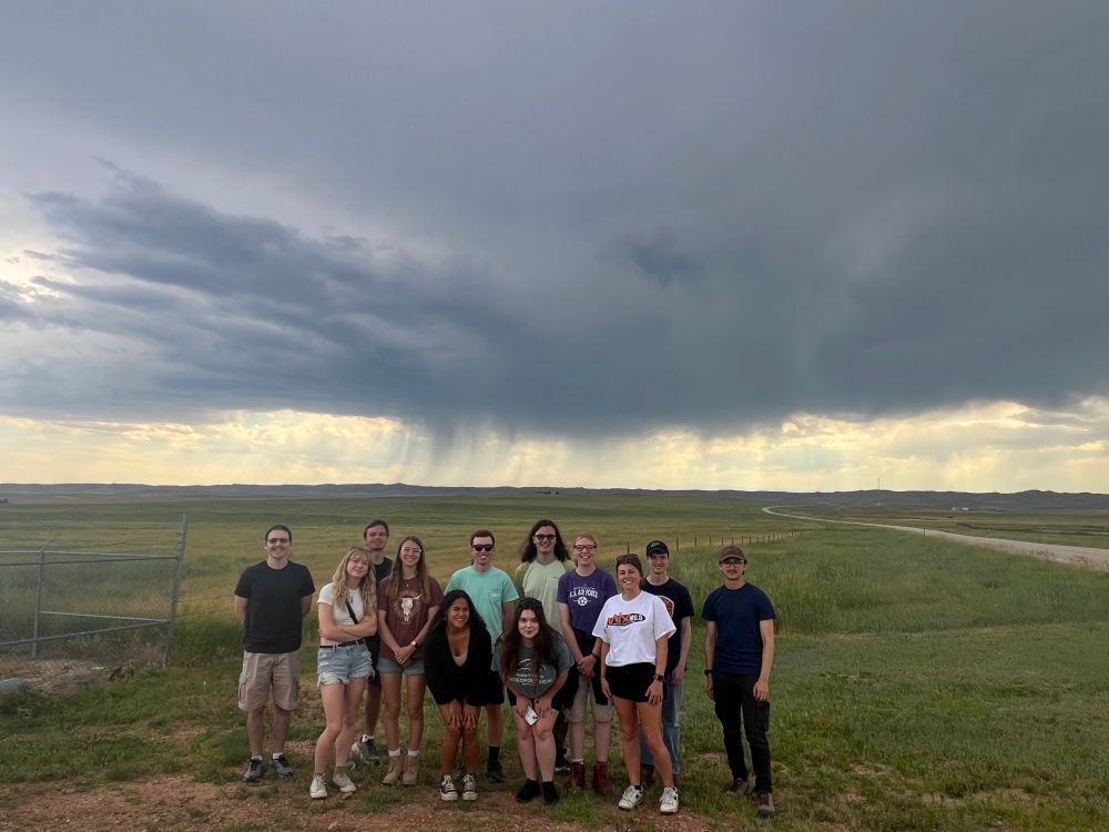 A group of people standing under a stormy sky.