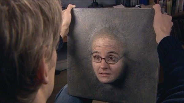 A scene from Dr Who where a woman’s face becomes implanted into a slab of concrete. She’s still alive and speaks, it’s very strange. She has glasses and looks understandably surprised at her situation.