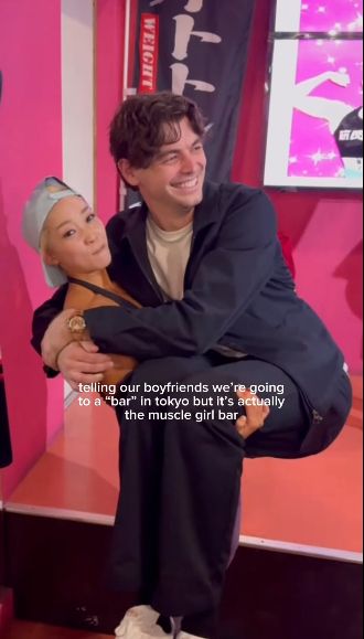 Tiny blonde muscly Japanese woman cradling top U.S. male tennis player Taylor Fritz like a baby with the caption "telling our boyfriends we're going to a 'bar' in tokyo but it's actually the muscle girl bar" (Photo: Morgan Riddle's IG)