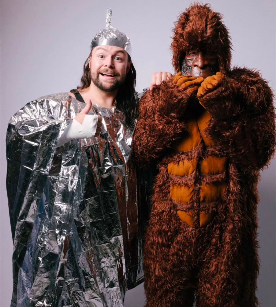 Eli Surge in his tin foil hat and cape flanked by his actual tag partner, a Sasquatch 