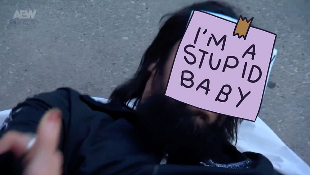 Wheeler Yuta emerging from a body bag with a sign stuck to his face that reads - I'm a Stupid baby