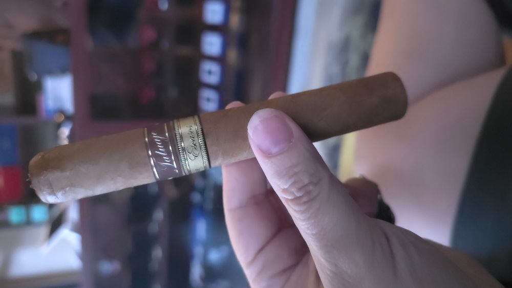 Tatuaje Escasos. In background is a pasty white leg and further background are display cabinets with lighters.