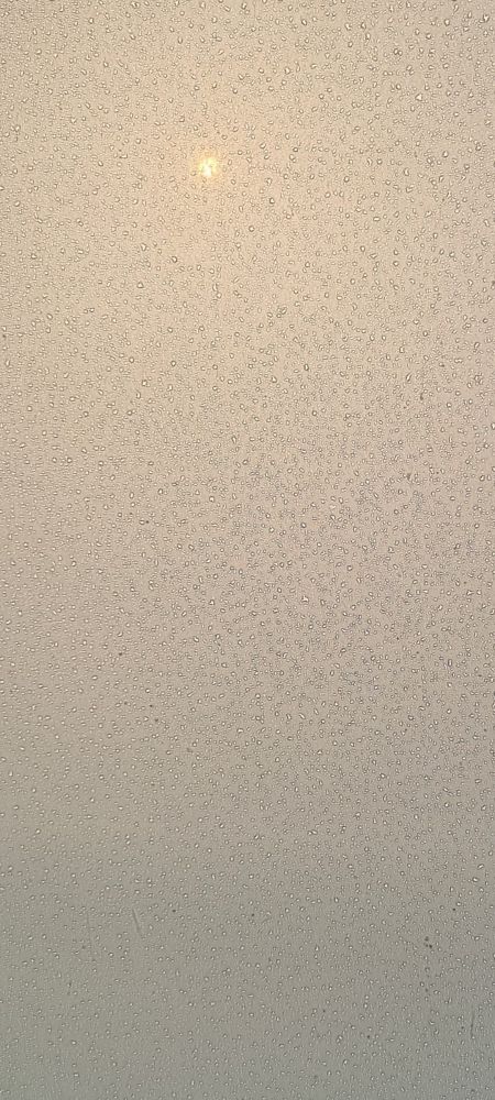 Sun seen through a raindrops on a misted window