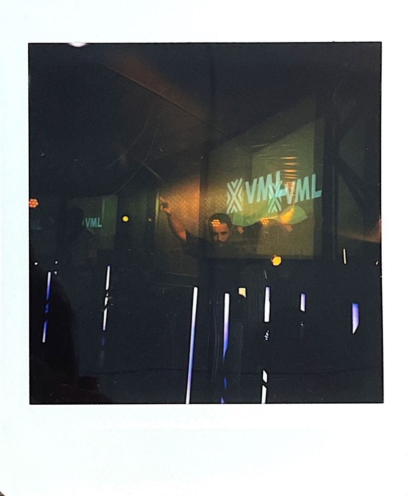 Classic square instant style photo with multiple exposures. the VML logo is seen floating multiple times with a DJ posing infront of it. Overall a trippy psychedelic vibe.