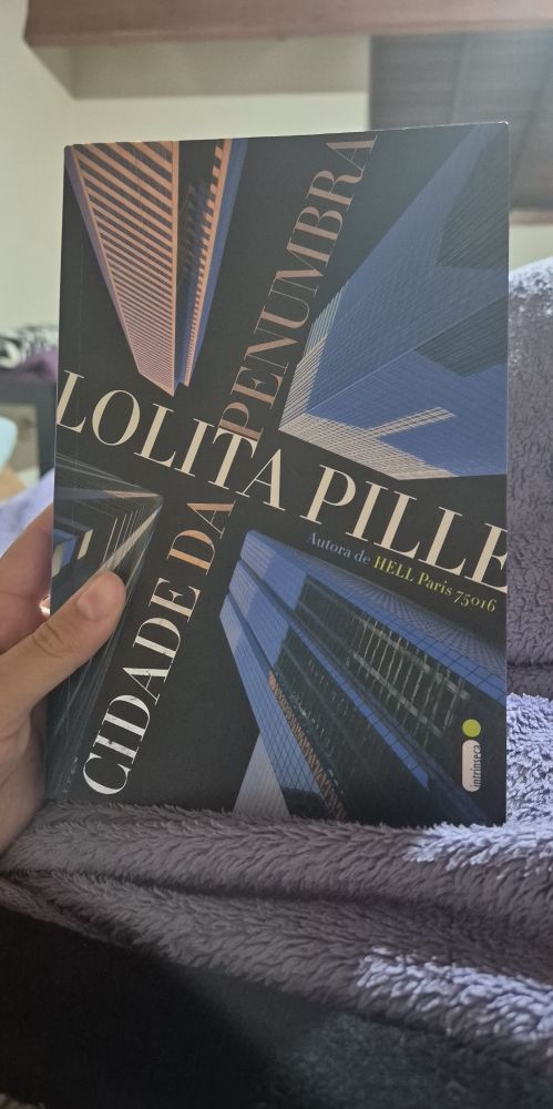 capa do livro "cidade da penumbra" de lolita pille. na capa tem uma ilustração de quatro prédios em uma perspectiva olhando de baixo pra cima. 