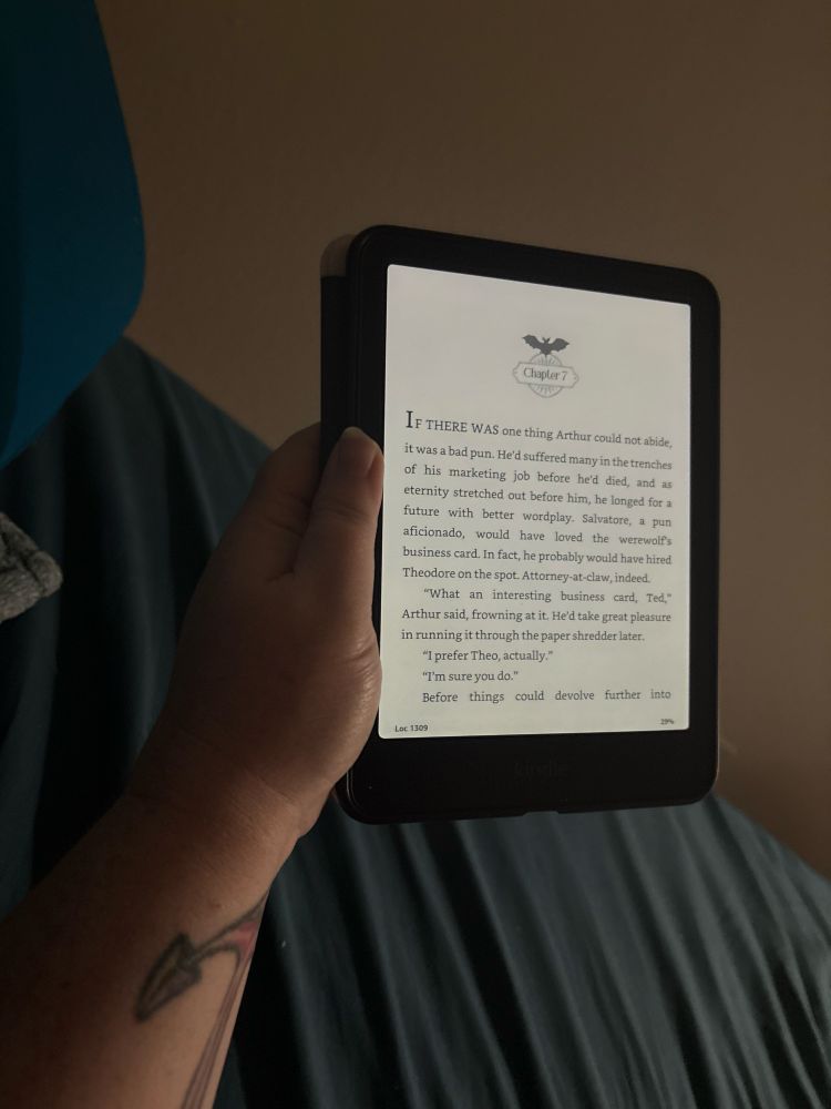 Photo of an e-reader displaying text from Chapter 7 of Dead & Breakfast by Kat Hillis and Rosiee Thorr. 