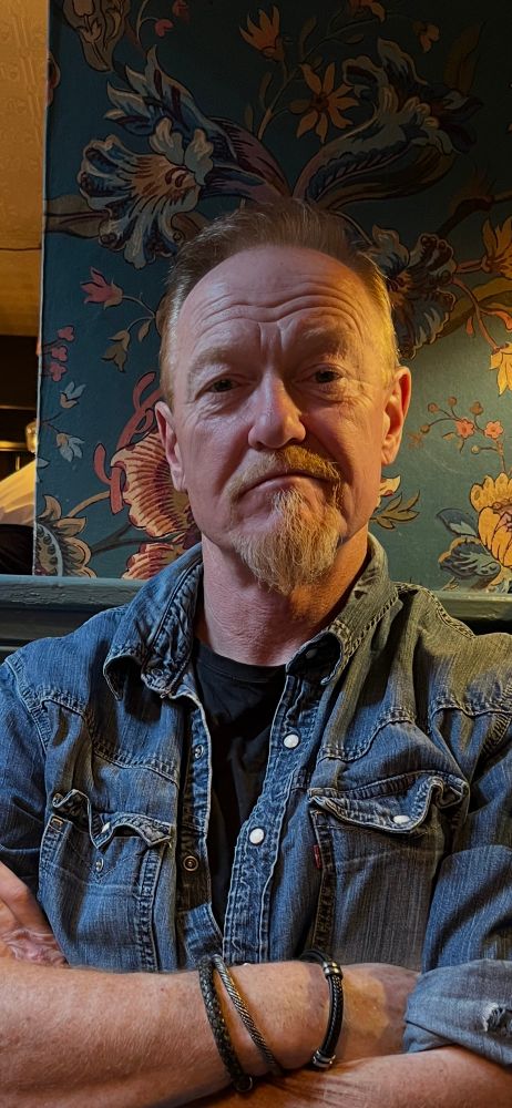 Picture of a man sitting in a pub, arms folded , looking very pensive! 