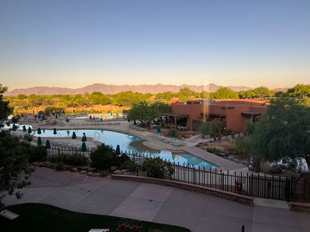 A mountain range in the background with a pool and a pool bar restaurant shown in the front