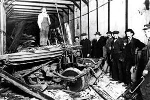 Men stand next to the debris from a train of wooden cars that derailed in a tunnel.