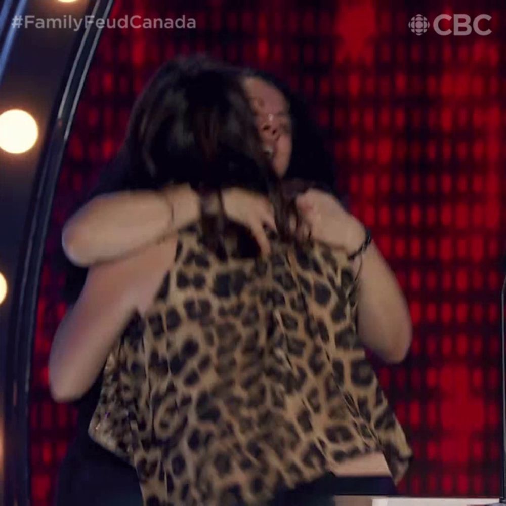 two women hugging each other with the words family feud canada on the bottom left