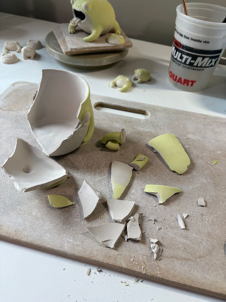 A piece of frog pottery that I was painting sits shattered in pieces on the table.