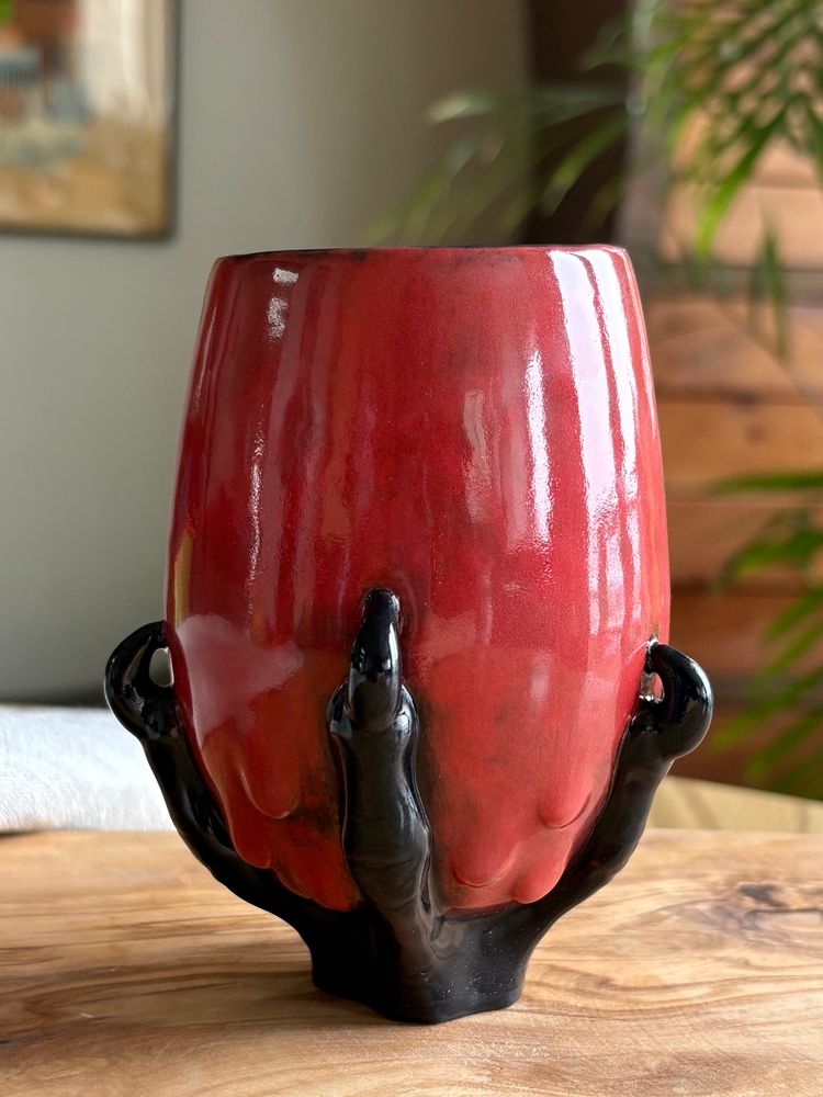 The red cup of the goblet is shaped like a wine glass, and a black animal claw is clutching the base.