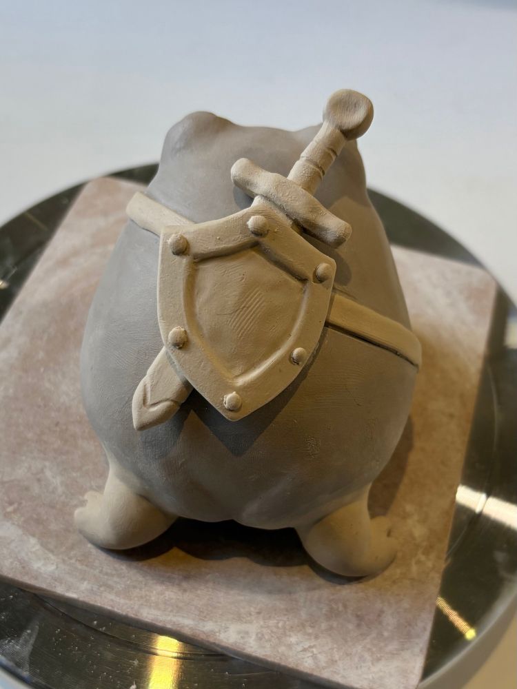 The sword and shield are now on the back of a clay frog.