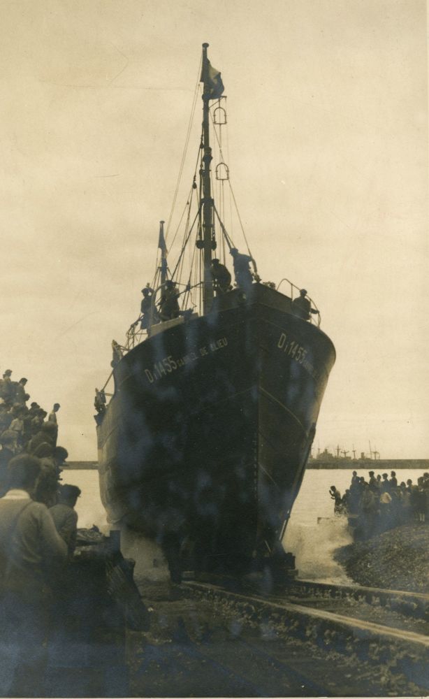 La coque du navire Gabriel de Clieu, poussé sur des rails, pénètre dans l'eau. Foule de part et d'autre des rails. Photographie sépia.