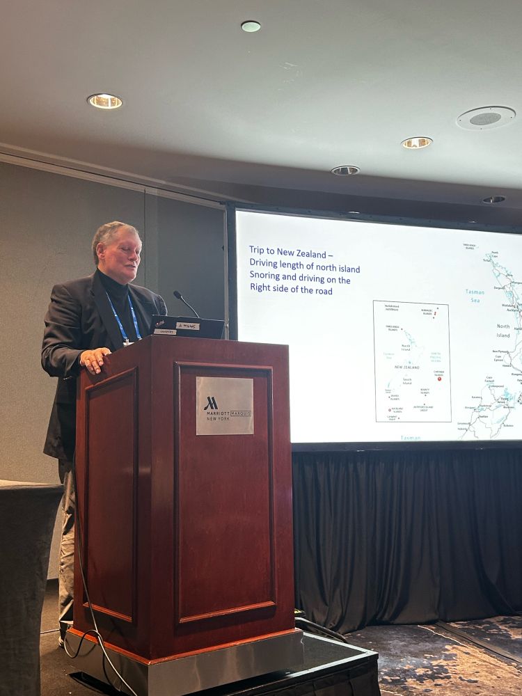 Dr. Randy Engle stands at a podium. His slide has a map of New Zealand.