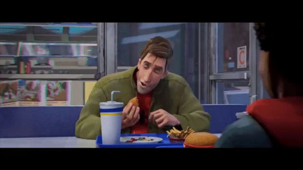 a man in a green jacket is eating a hamburger and french fries at a fast food restaurant