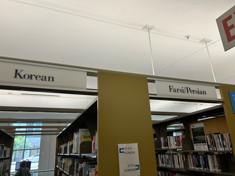 Photo showing library bookshelves labeled Korean and Farsi/Persian