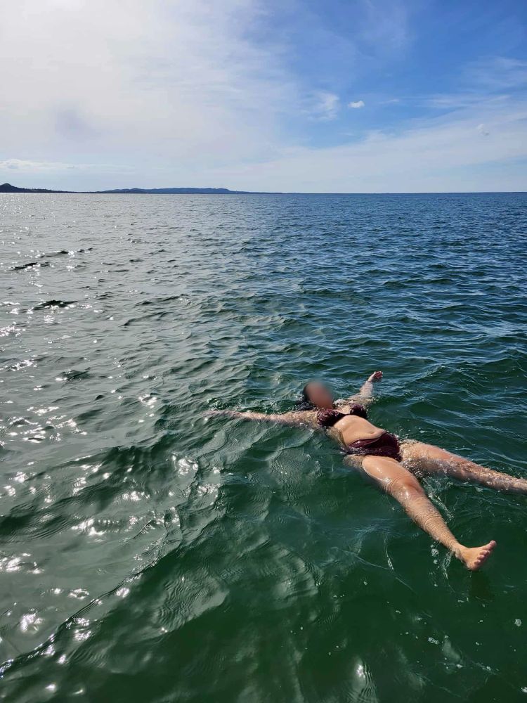 GFE provider Estelle Laflamme in a red bikini floating on her back in the big blue sea with blue skies ahead . 