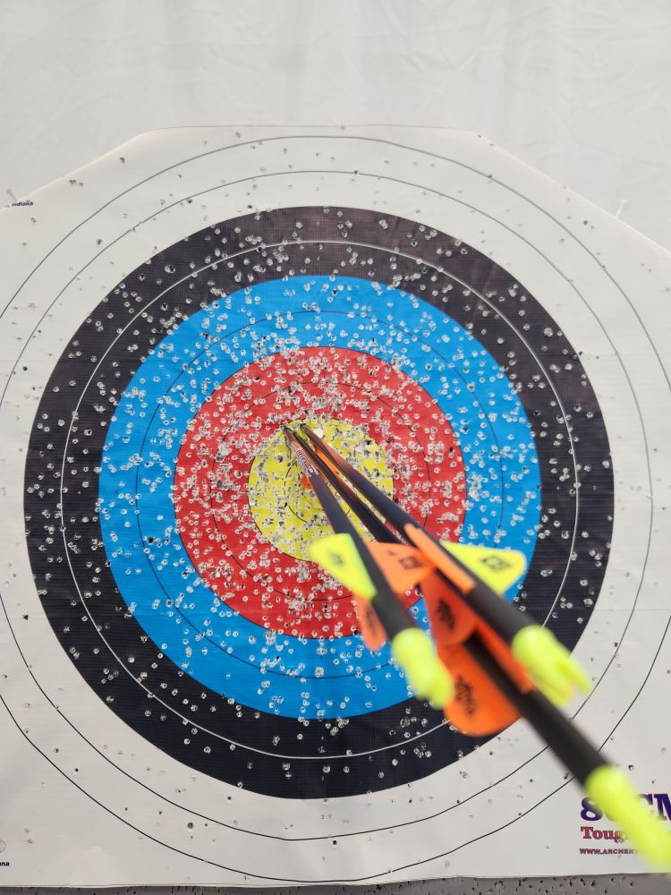 Three arrows in a target, all clustered in the middle/top left of the center yellow part of a target