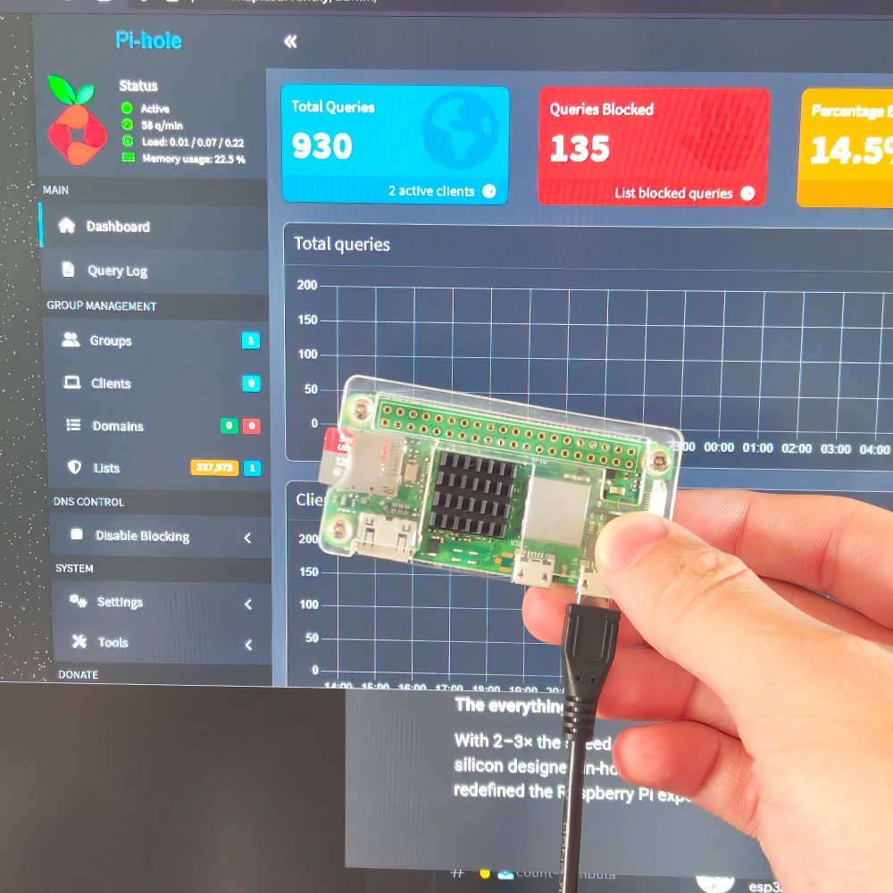 holding a raspberry pi zero w in front of my monitor, which has the pi-hole admin dashboard open
