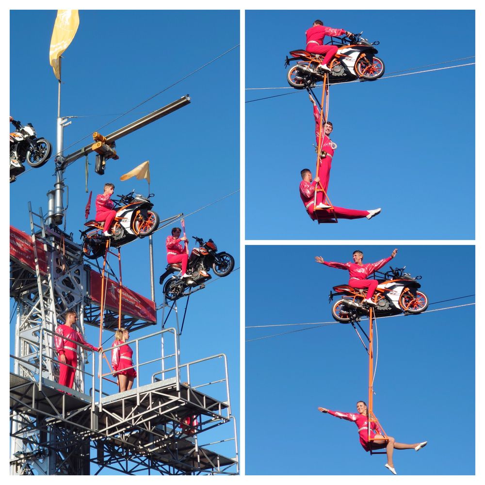3er Collage vor blauem Himmel, linkes Foto zeigt eine Platform mit oben angebrachten Motorrädern, darunter stehen 2 Artisten. Rechts oben fährt das Motorrad auf dem Seil, während an einer Vorrichtung darunter 2 Artisten stehen bzw 1 steht und 1 sitzt. Das rechte untere Bild zeigt oben wieder das Motorrad mit dem Fahrer, der die Arme zur Seite hält, während eine Artistin in Schaukel unter ihm sitzt und ebenfalls einen Arm zur Seite hält.