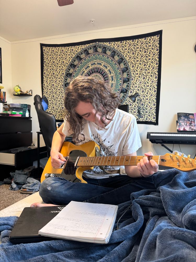 Picture guitar playing notebook bedroom tapestry sitting on bed music sound instrument jeans picture focus 