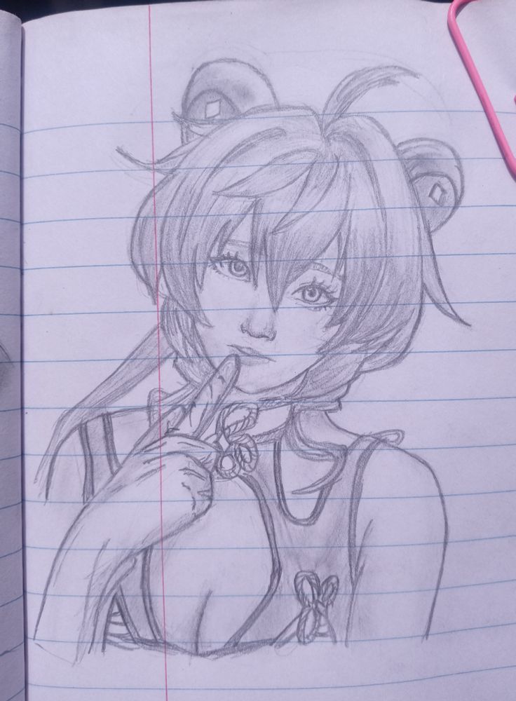 A pencil drawing of Ganyu, an anime-style girl with short, layered hair, goat horns, and expressive eyes. She is holding two fingers near her lips in a playful gesture. The drawing is detailed, with shading on her hair, clothes, and skin. The artwork is sketched on lined notebook paper with a pink paperclip on the top right corner.