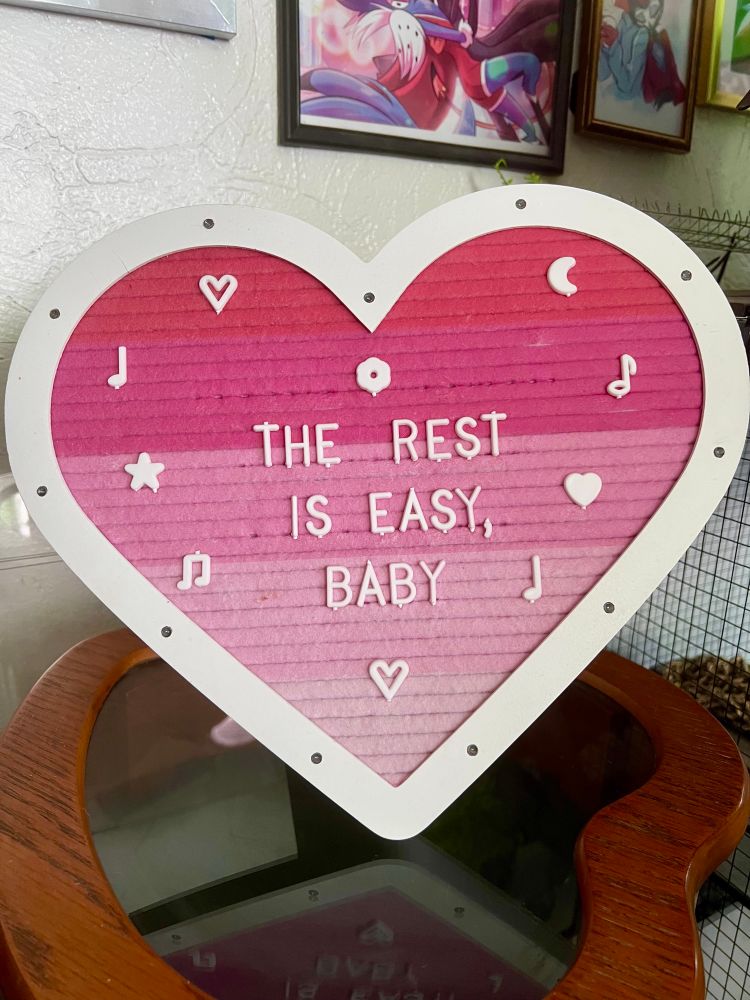 Heart shaped letter board that reads “the rest is easy, baby” and is decorated with hearts, music notes, star, moon, and flowers 