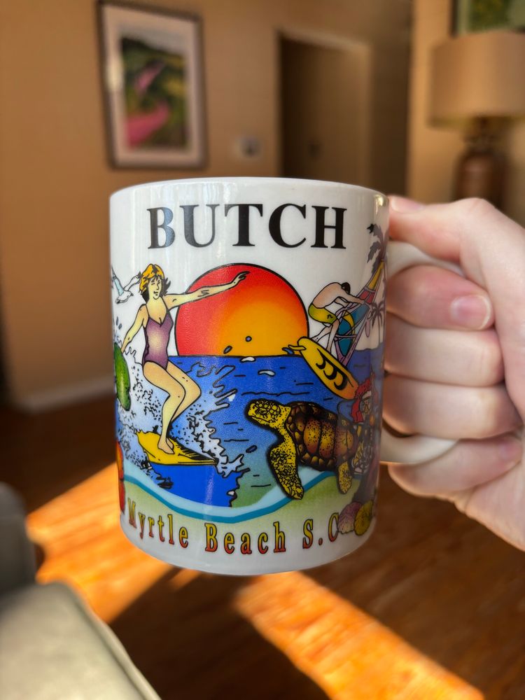 Touristy souvenir coffee mug from Myrtle Beach, SC depicting beach vacation scenes that also has the word BUTCH on it in big letters