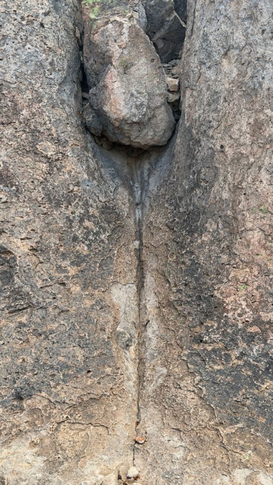 Rock formations of two massive boulders with a vertical crack between them and another boulder, resting at the top of that crack in the City of Rocks, Faywood, New Mexico.
