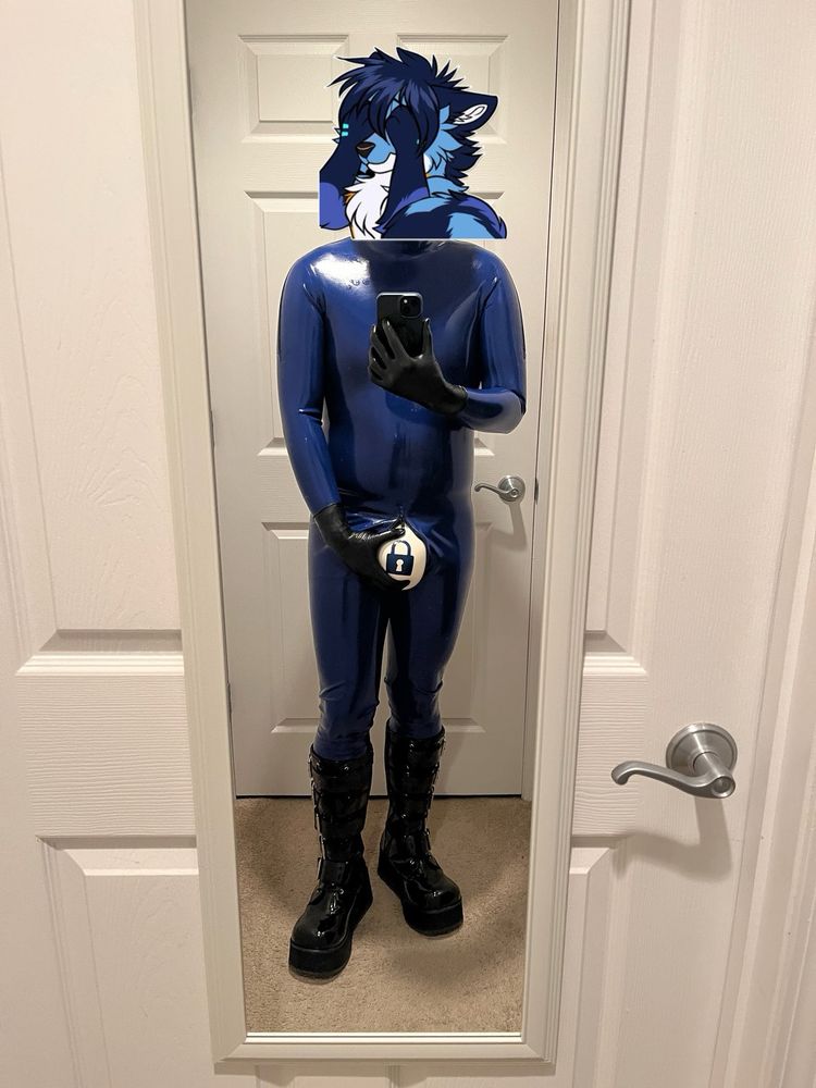 Me in my blue latex catsuit, knee high black platform boots, and a white inflatable null bulge undie under the catsuit, with a blue padlock symbol on it. My right hand is squishing on the null bulge