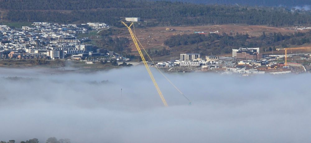 A yellow Crane emerges out of the top of the fog at Coppins crossing.
