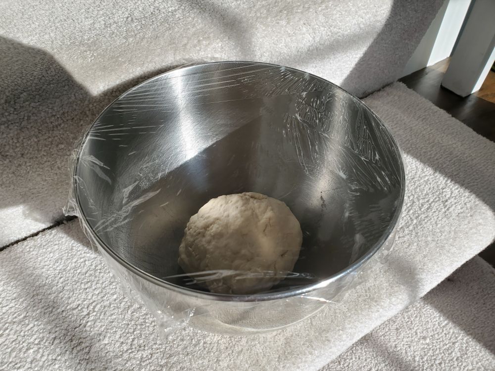 A ball of dough in a metal bowl.