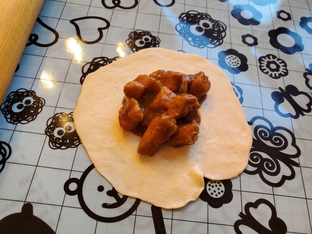 Simmered pork cubes in sauce on an open steamed buns wrapper