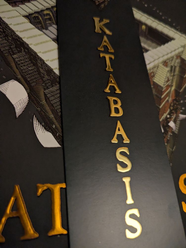 A bookmark labeled katabadis in raised gold lettering in front of the similarly titled book. It's very nice