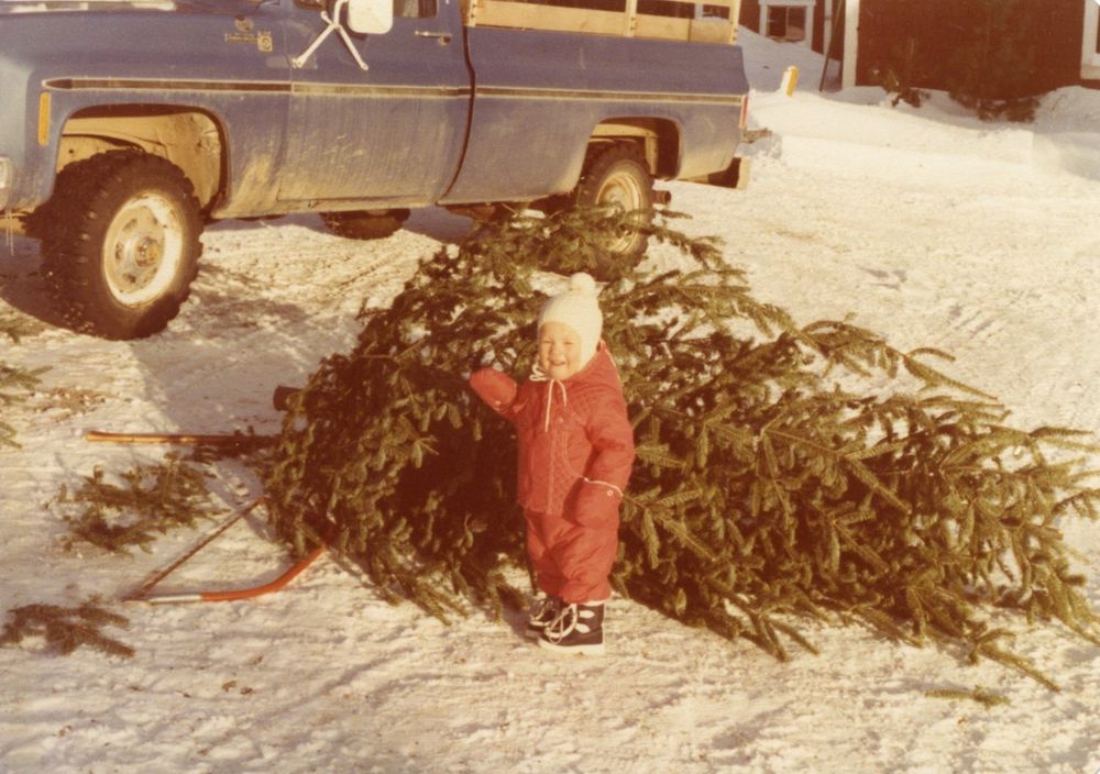 Daughter with Christmas tree and farm pickup truck in the background.