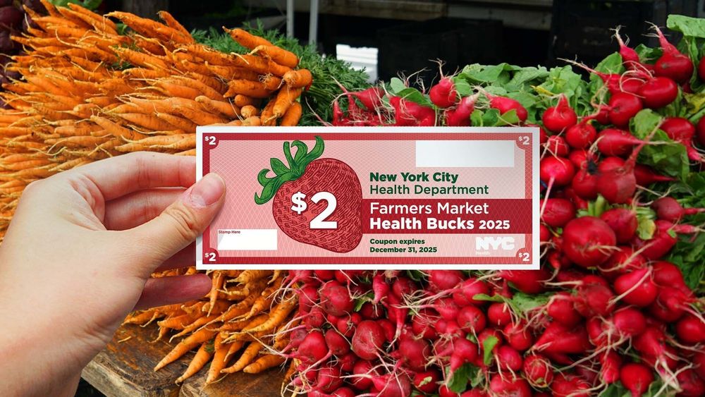 
A close-up photograph shows a hand holding a $2 New York City Health Department Farmers Market Health Bucks coupon against a vivid background of fresh produce.

The coupon features a prominent red strawberry graphic with "$2" written on it. The text on the coupon, which is white and red, reads: "New York City Health Department Farmers Market Health Bucks 2025" and "Coupon expires December 31, 2025."

The background is filled with bunches of bright orange carrots on the left and piles of red radishes with green tops on the right.