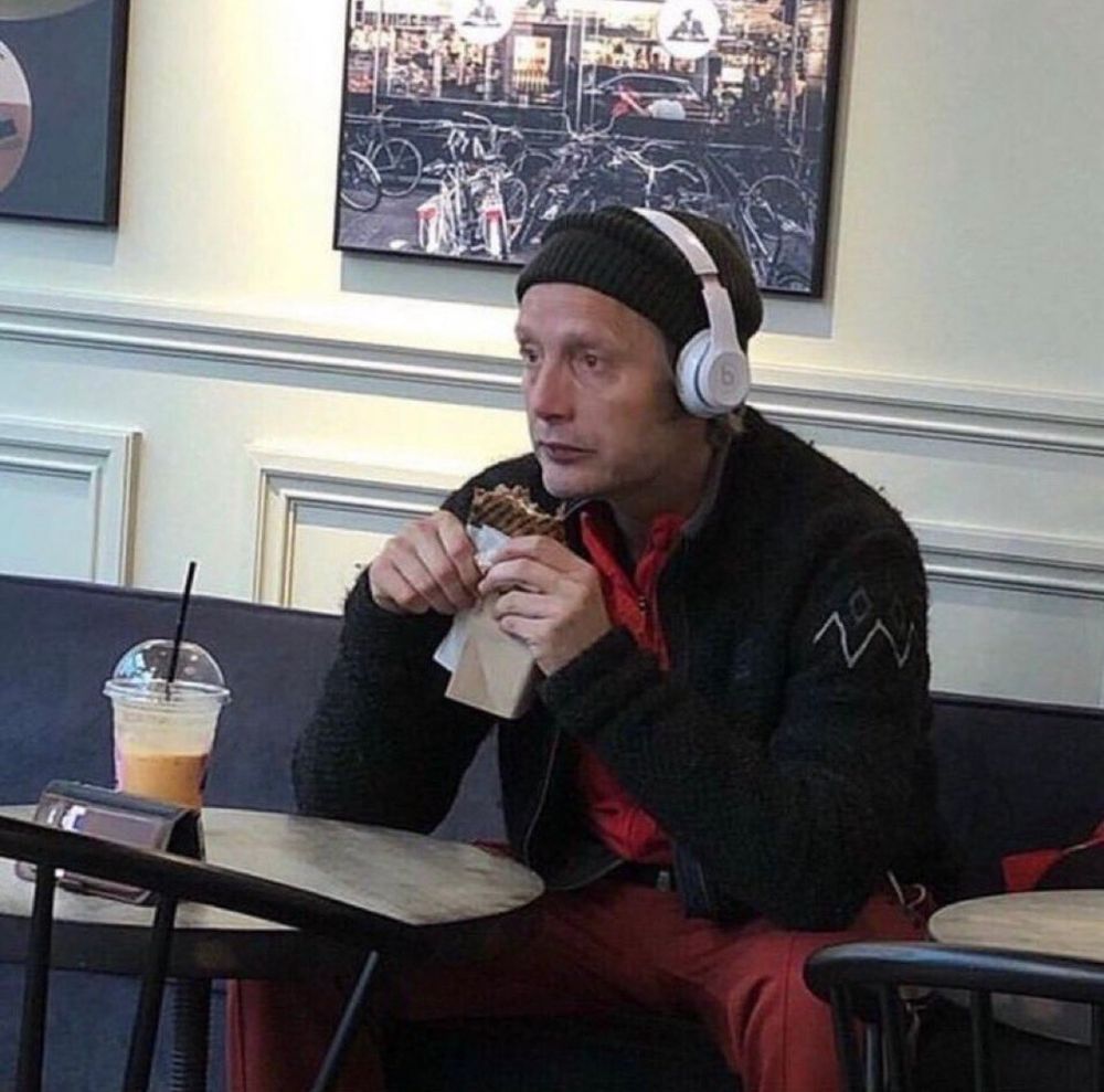 Mads Mikkelson eating a sandwich and staring blankly into space 
