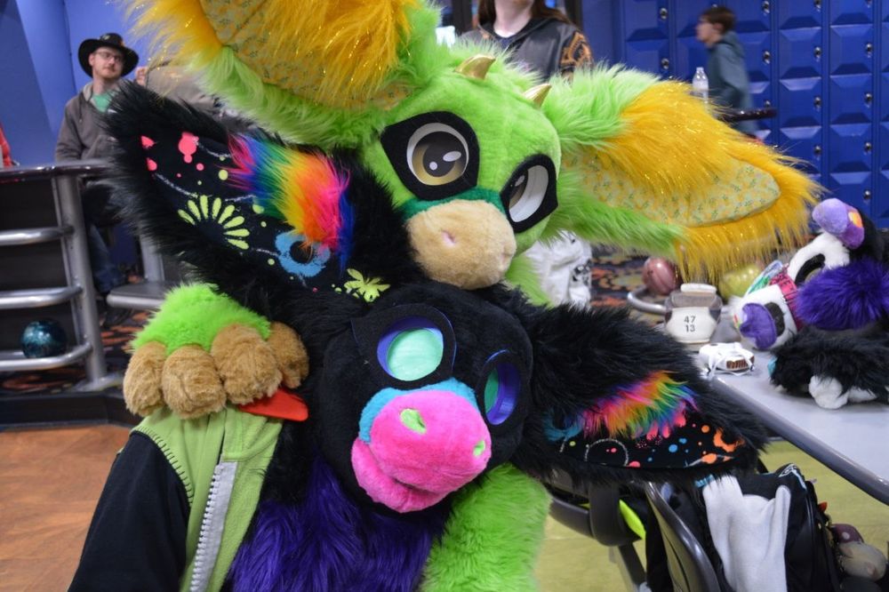 Two fursuiters with their heads on top of each other