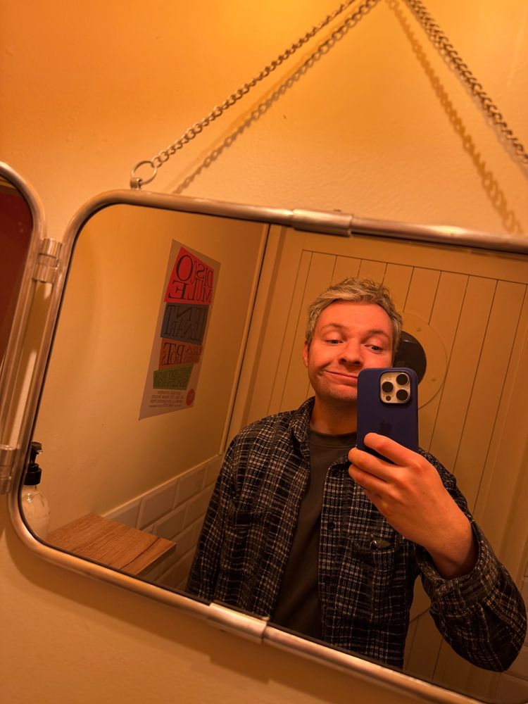 Me smiling while taking a selfie in a bathroom mirror.