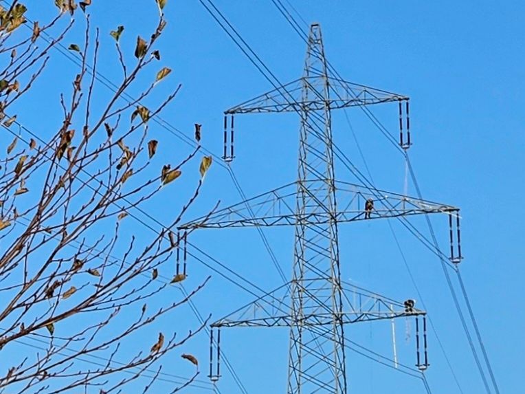 Ein Strommasten mit zwei Monteure 