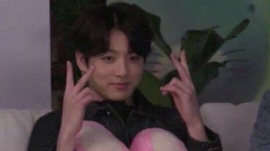 jungkook of bts throwing up a double bunny 