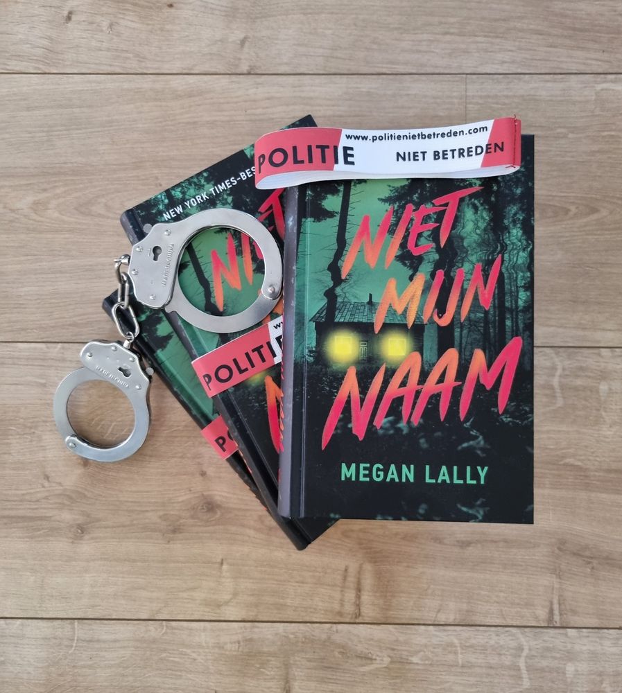 Three books of Dutch translation "Niet mijn naam" by Megan Lally, pictured on a wooden floor with pair of handcuffs as accessory.
