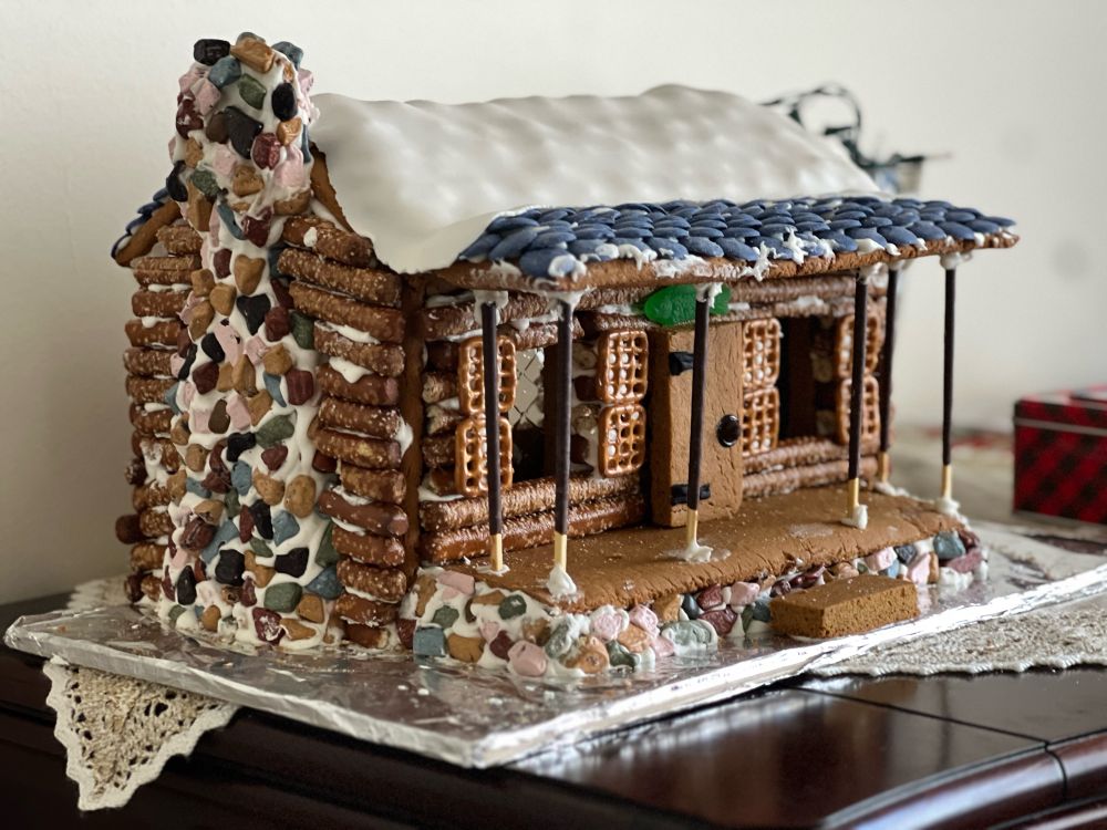 An elaborately decorated gingerbread house. There is snow on the roof. 