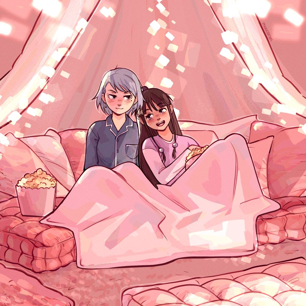 Franziska and Maya cuddling together under blankets with popcorn.