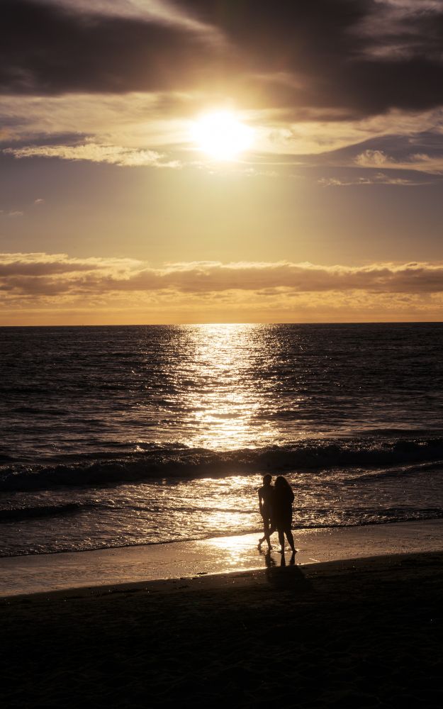 Two people standing along the shore of a beach