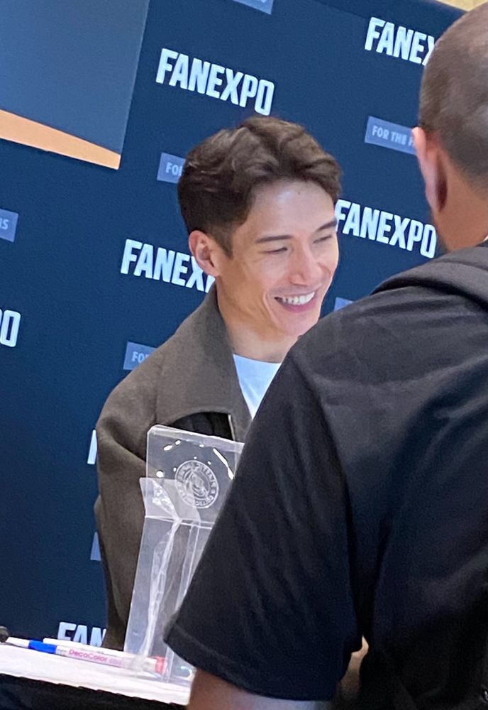 Manny Jacinto smiling as he signs an autograph