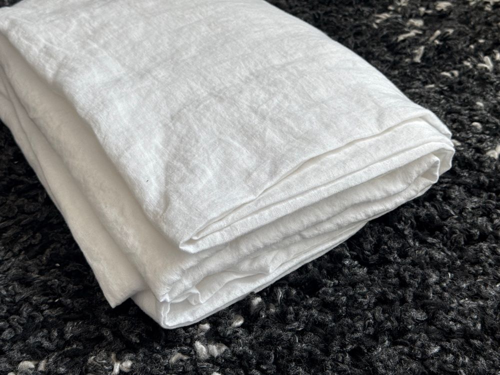 A perfectly folded fitted sheet on a dark gray carpet